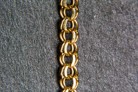 A gold chain against a black textured background.
