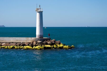 A lonely man near the lighthouse on the wave-breakers in Istanbulの写真素材