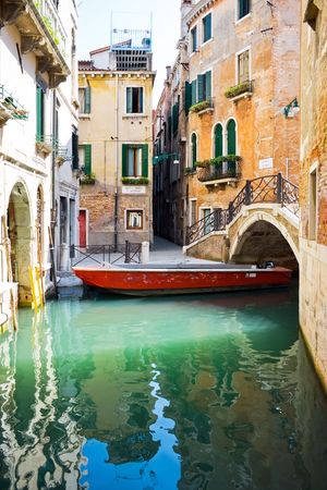 Small bridge over blue and green water of a venetian canal, Italyの写真素材