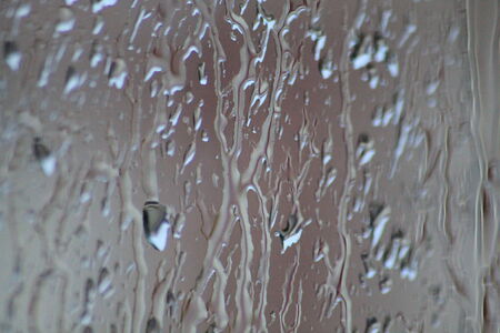 rain streaking down the window obscuring the world beyondの写真素材