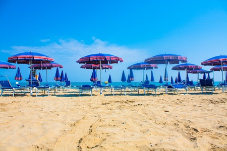Adriatic Sea coast view. Seashore of Italy, summer umbrellas on sandy beach with clouds on horizonの写真素材