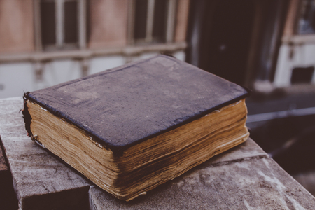 Vintage old book on stone, grunge textured cover. Retro styled image with blurred backgroundの写真素材