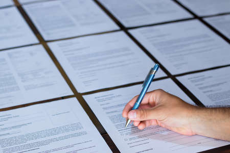 Costa Rican Hand of a young adult man signing a stack of contract or agreement papers with a metallic blue penの写真素材