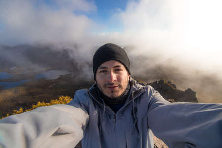 Hiker man selfie with winter clothes and a landscape of the valley with lakes and rocky mountains...
