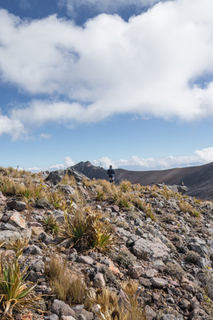 man in the distance with rocky mountains on a sunny dayの写真素材
