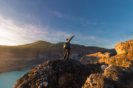 Mountaineer man taking a selfie in Poas Volcano Crater Lagoon at sunrise surrounded by volcanic rocks in Poas Volcano National Park in Alajuela province of Costa Ricaの写真素材