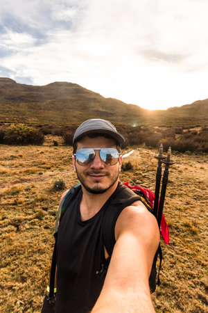 vertical shot of adult male hiker wearing sunglasses taking a selfie at sunrise in Chirripo National Park in Costa Ricaの写真素材
