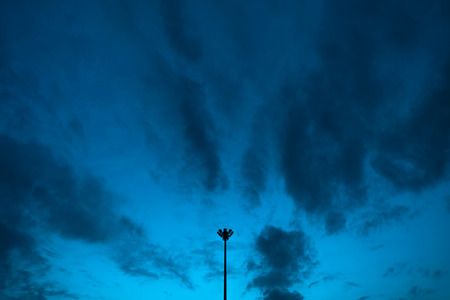 Evening cloudy sky with a single light pole. Lights off. Symmetry balanced in centre.の写真素材