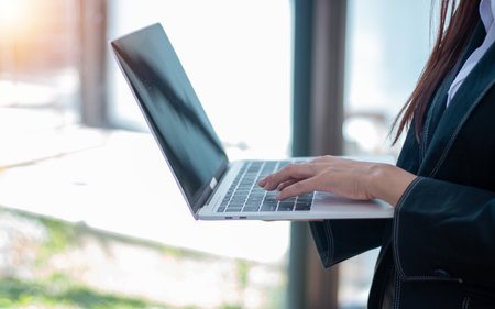 Close up of businesswoman hands typing on laptop computer in office.