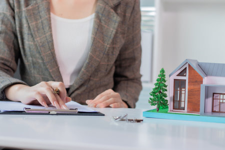 Real estate agent working with house model and writing on paper in officeの写真素材