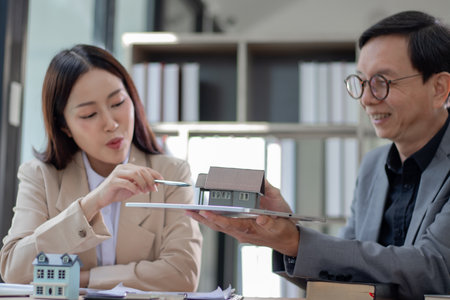 A real estate business woman and man sign a house contract and explain their housing project.の写真素材