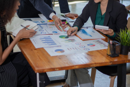 Group of business people discussing the charts and graphs showing the results of their successful teamworkの写真素材