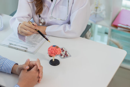 A female doctor is using a brain model and explaining nerve treatments to young men who are being treated at a neurology hospital or specialist clinic.の写真素材