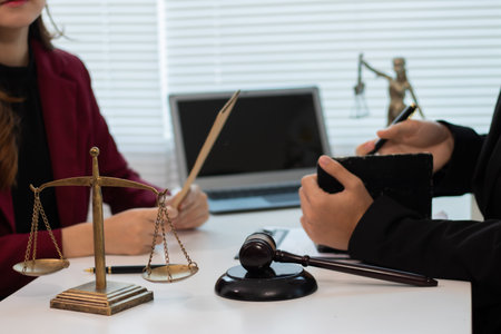 Male and female legal consultants work intently together over documents and laptops in a law office.の写真素材