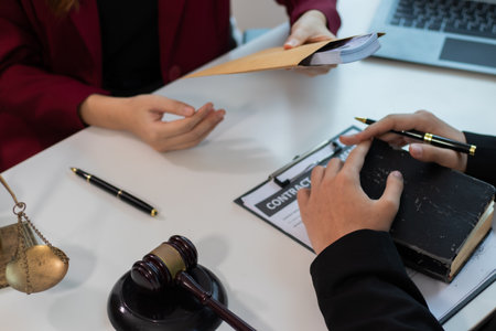 Male and female legal consultants work intently together over documents and laptops in a law office.の写真素材