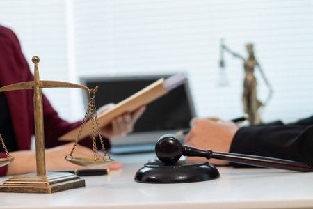 Male and female legal consultants work intently together over documents and laptops in a law office.の写真素材