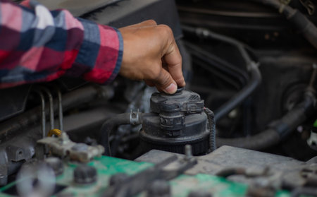 Auto mechanic working in auto repair service. Closeup of car mechanic hands checking car engine.の写真素材