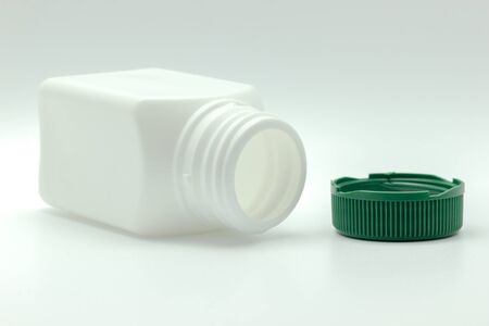 White bottle of antibiotic and green bottle cap placed on a white background.の写真素材