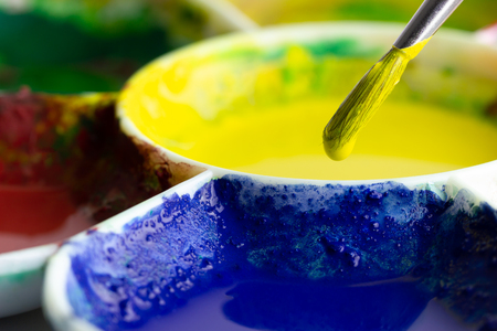 The brush is dipped in yellow color and the palette on a white background. Suitable for background, articles about artistic.の写真素材