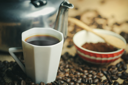 Coffee cup and hot pot. Roasted coffee beans on brown wood background in morning.の写真素材