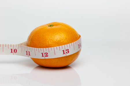Closeup tangerine was wrapped around it with measuring tape. The concept of love and health care or diet.の写真素材