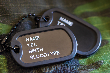 Soldier tag or dog tag laid on military jacket and morning sunlight. Concept of protecting for a new day.の写真素材