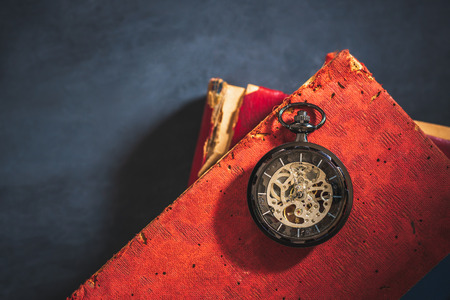 Pocket watch and old book on cement floor. Top view and copy space for text. Concept of time and...