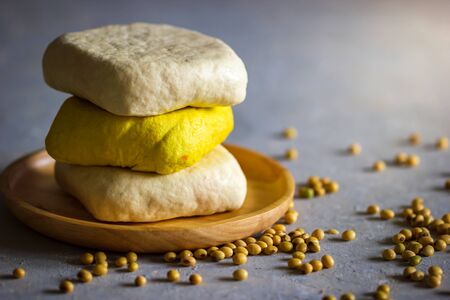 Tofu stacking on wooden dish with morning sunlight and soybean seeds scattered on the table. Healthy...