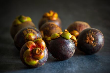 Mangosteen on black cement floor and morning light. Is a seasonal fruit in Thailand. Closeup and copy space for text.の写真素材