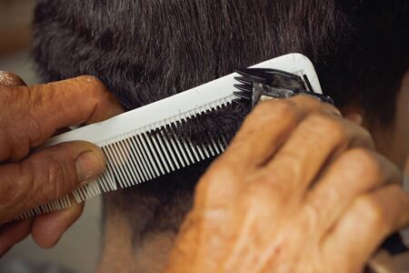 Closeup hand of hairdresser cutting hair with clipper at local barber shop.の写真素材