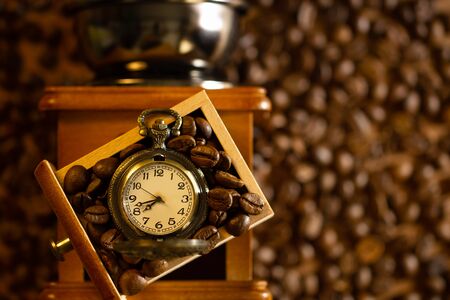 Coffee bean and pocket watch the tray of manual grinder on table. Top view and copy space. Concept of coffee time in morning.の写真素材
