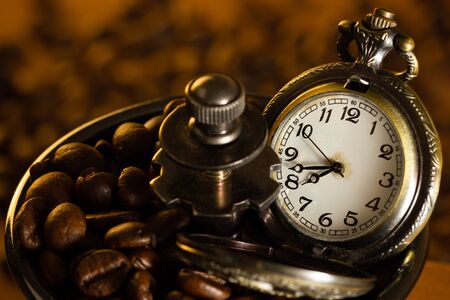 Coffee bean and pocket watch the tray of manual grinder on table. Closeup and copy space. Concept of coffee time in morning.の写真素材