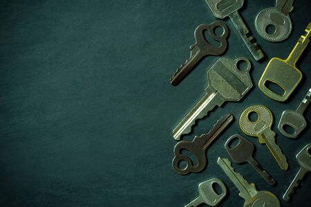 Different variety of vintage keys are placed on black wooden floor in darkness background. Closeup...