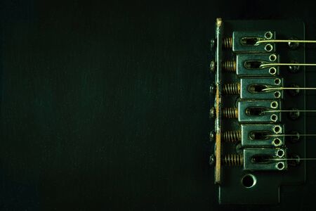 A closeup rust bridge serves to fasten or tighten the string. Black vintage electric guitar in dark. Top view and copy space. Concept of good memory About retro musical instruments and rock music.の写真素材