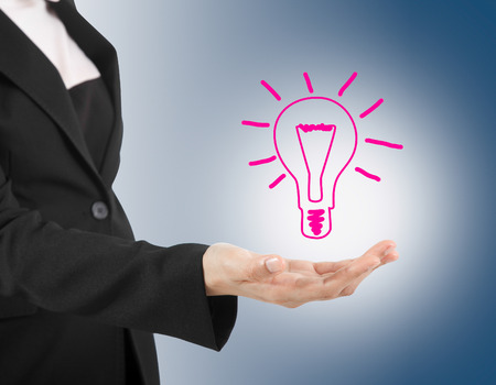 Light bulb in hand business woman on blue background の写真素材