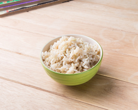 a bowl of rice with a book rests on a wooden desk の写真素材