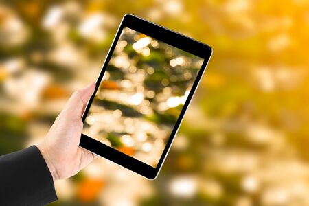 Touch screen in hand on yellow bokeh  background.