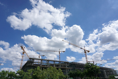 Construction cranes on cloudy background.