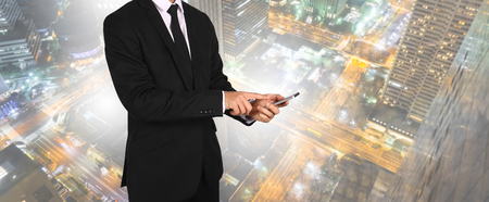 Touch screen in hand businessman on city night light. Connection concept.の写真素材