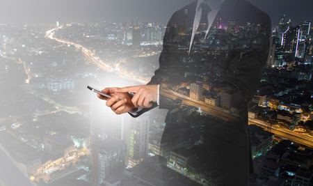 Touch screen in hand businessman on city night light. Connection concept.の写真素材