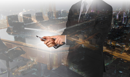 Touch screen in hand businessman on city night light. Connection concept.の写真素材