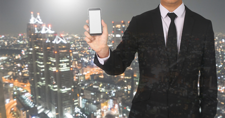 Businessmen Handle a Tablet of Confidence in the Cityscape of Night Lights.の写真素材