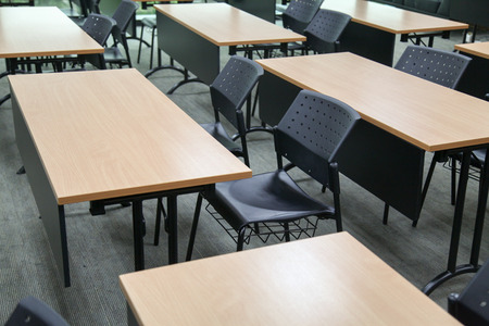Table in a seminar room arranged in lined with chairs.