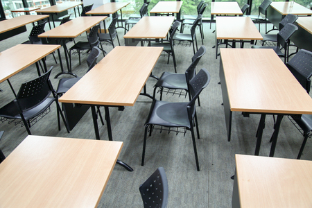 Table in a seminar room arranged in lined with chairs.の写真素材