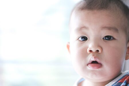 An Asian baby is wondering in the morning sunshine - Focus piont and Light fair concept.の写真素材