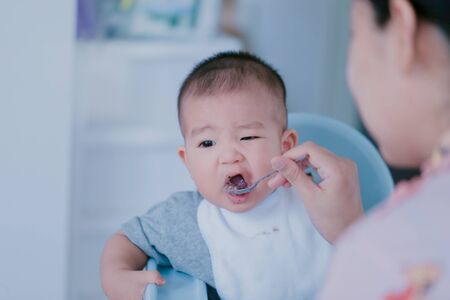 The baby is eating deliciously fed by the mother - Bright tone and focus point concept.の写真素材