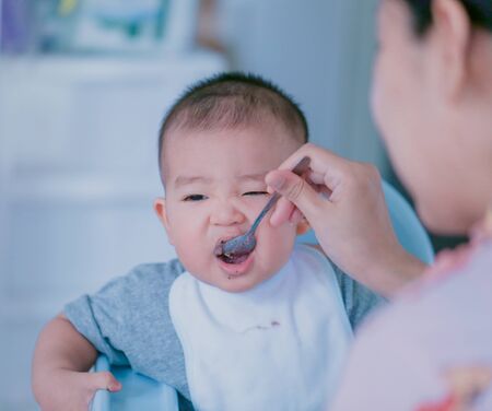 The baby is eating deliciously fed by the mother - Bright tone and focus point concept.の写真素材