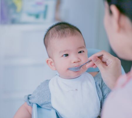 The baby is eating deliciously fed by the mother - Bright tone and focus point concept.の写真素材