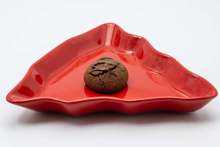 A homemade chocolate covered cookie in a red plate. The background is white.の写真素材