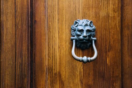 Front view of a vintage door knocker on a solid old wooden door.の写真素材